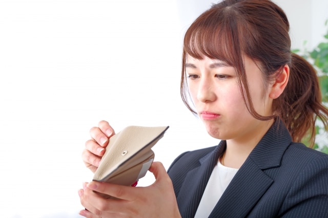 財布の中を覗き込む若い女性